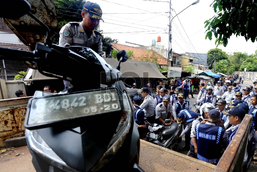  Petugas Dinas Perhubungan DKI Jakarta mengangkut motor yang nekat parkir di bahu jalan di Kawasan Kebon Kacang, Tanah Abang, Jakarta Pusat, Senin (12/10).   (Republika/Yasin Habibi)