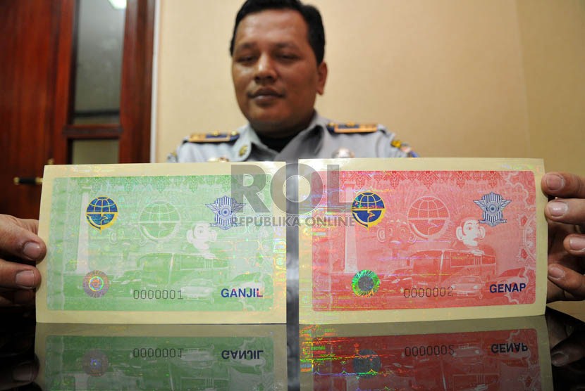   Petugas Dinas Perhubungan DKI Jakarta menunjukkan stiker ganjil genap berhologram di Jakarta, Kamis (7/3).   (Republika/Prayogi)