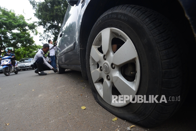 Petugas Dinas Perhubungan mengempeskan sebuah mobil yang terparkir liar di Jalan Bungur Besar, Jakarta Pusat, Rabu (23/3). 