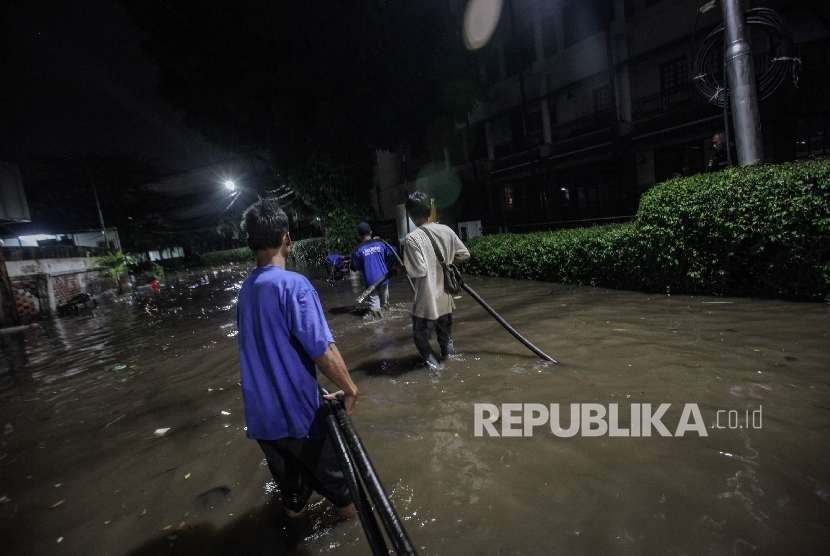 Petugas Dinas Tata Air  DKI memasang pompa penghisap air di Kawasan Kemang, Jakarta, Ahad malam  (25/9).