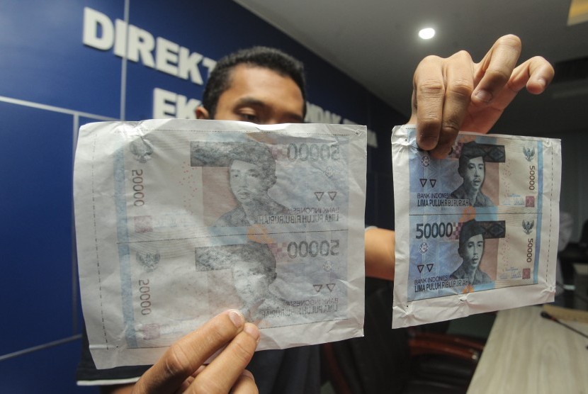 Police officer shows counterfeit money during a release at National Police headquarters, Jakarta, Friday (June 16). 