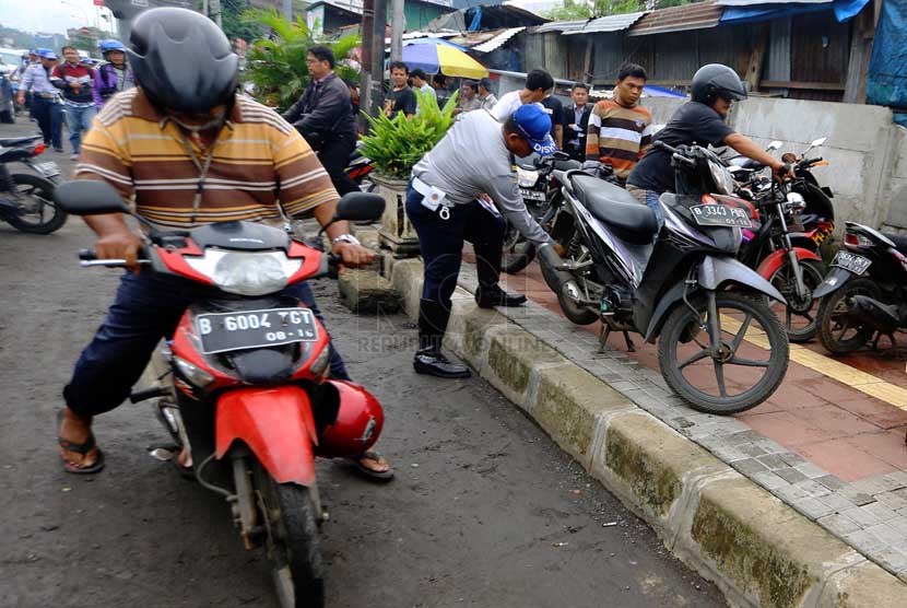   Petugas Dishub DKI mencabut pentil ban motor dan mobil yang parkir sembarangan di Jalan Matraman, Jakarta Timur, Senin (10/3).   (Republika/Yasin Habibi)