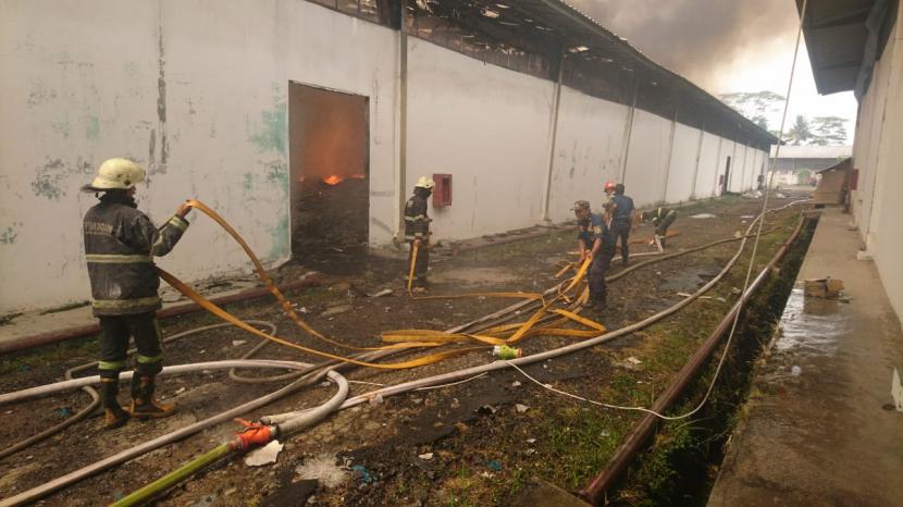 Petugas Diskar PB sedang berjuang memadamkan api di gudang pabrik kapas. 