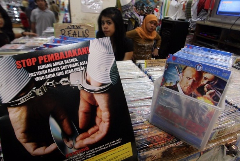 Petugas Ditjen HKI (Hak Kekayaan Intelektual) KemenKumHam menempelkan gambar sosialisasi Anti Pembajakan di toko - toko penjual Software dan DVD Bajakan di Mall WTC Serpong, Serpong, Tangerang Selatan, Banten, Rabu (19/6).