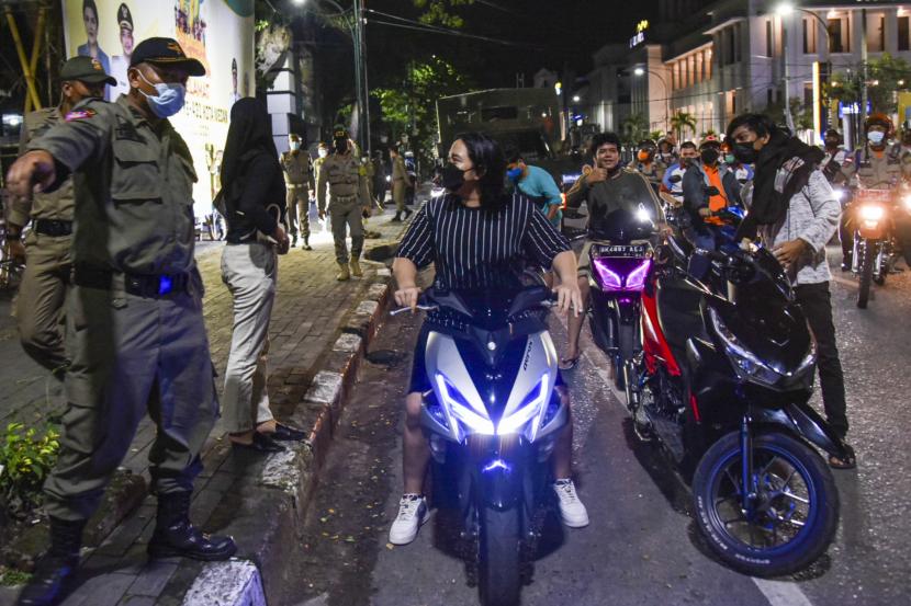 Petugas gabungan dari Kepolisian dan Satpol PP membubarkan pengendara roda dua yang berkumpul saat pemberlakuan Pembatasan Kegiatan Masyarakat (PPKM) Darurat di Kawasan Kesawan, Medan, Sumatera Utara, Senin (12/7/2021) malam. Razia tersebut bertujuan untuk mengendalikan penyebaran COVID-19 selama masa PPKM darurat di Medan.