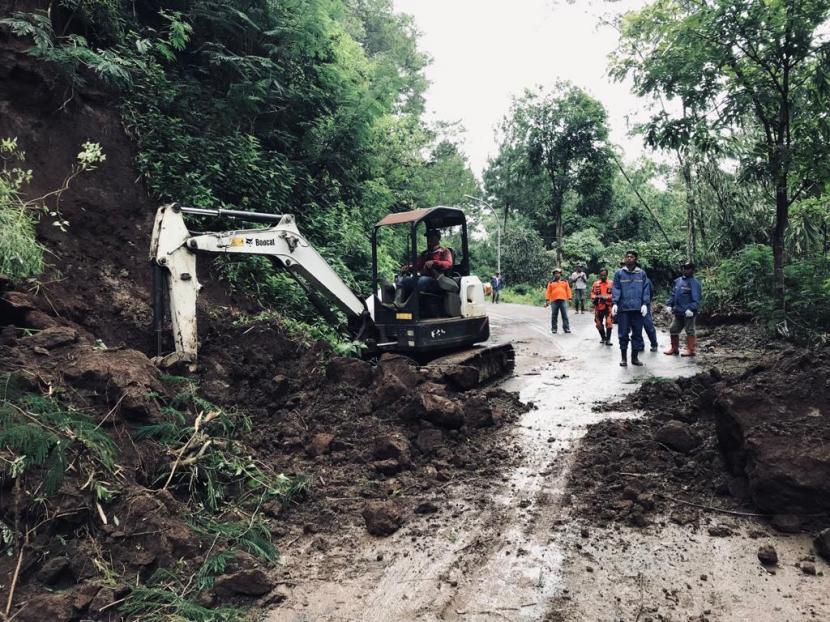 Petugas gabungan melakukan pembersihan material tanah longsor di Jalan penghubung Dusun Brau - Dusun Claket, Desa Gunungsari, Kecamatan Bumiaji, Kota Batu, Kamis (2/3/2023). 
