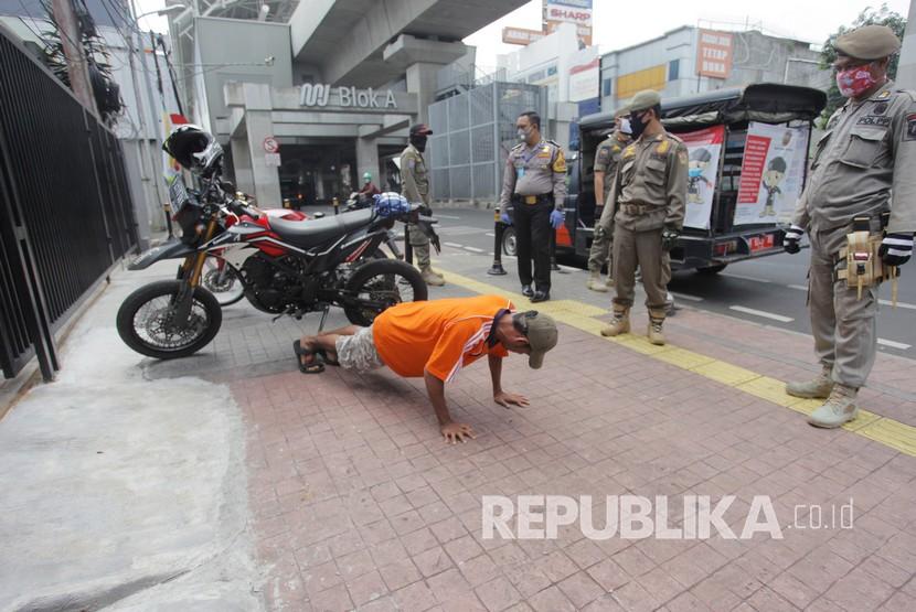 Petugas gabungan memberikan hukuman push up kepada warga yang tidak memakai masker saat razia Pembatasan Sosial Berskala Besar(PSBB) di Kawasan Jalan Fatmawati, Jakarta, Selasa (28/4/2020). Penertiban tersebut terkait pelaksanaan Pembatasan Sosial Berskala Besar(PSBB) di wilayah Jakarta dan memutus rantai penyebaran COVID 19.