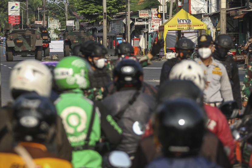 Petugas gabungan memeriksa ejumlah pengendara sepeda motor dengan latar belakang kendaraan taktis jenis barracuda dan panser yang disiagakan di pos penyekatan perbatasan Depok dan Jakarta di Jalan Raya Bogor, Jakarta Timur, Selasa (6/7/2021). Petugas Gabungan Polri dan TNI menyiapkan kendaraan taktis untuk membantu penyekatan selama PPKM Darurat Jawa - Bali.