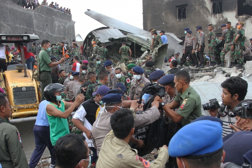 Petugas gabungan mengangkat kantong jenazah korban pesawat Hercules C-130 yang jatuh di Jalan Jamin Ginting, Medan, Sumatera Utara, Selasa (30/6). . (Antara/Irsan Mulyadi)