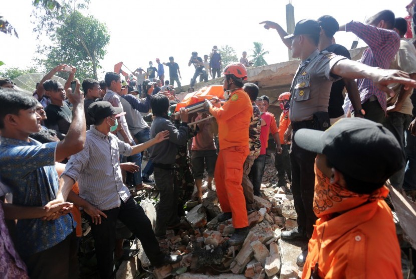 Petugas gabungan mengevakuasi korban dari bangunan yang runtuh akibat gempa 6.5 SR, di Desa Lueng Putu, perbatasan Pidie-Pidie Jaya, Aceh, Rabu (7/12).