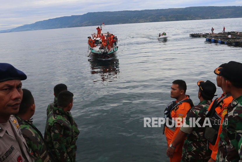 Petugas gabungan menunggu kapal SAR yang membawa kantong berisi jenazah korban KM Sinar Bangun yang tenggelam, bersandar di Pelabuhan Tigaras, Simalungun, Sumatera Utara, Rabu (20/6).