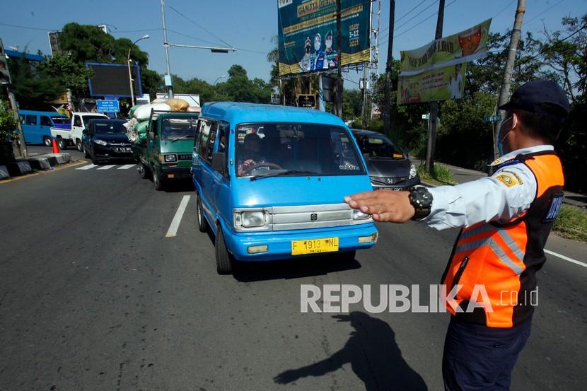 Petugas gabungan mengalihkan kendaraan di Jalan Raya Puncak, Gadog, Ciawi, Kabupaten Bogor, Jawa Barat.
