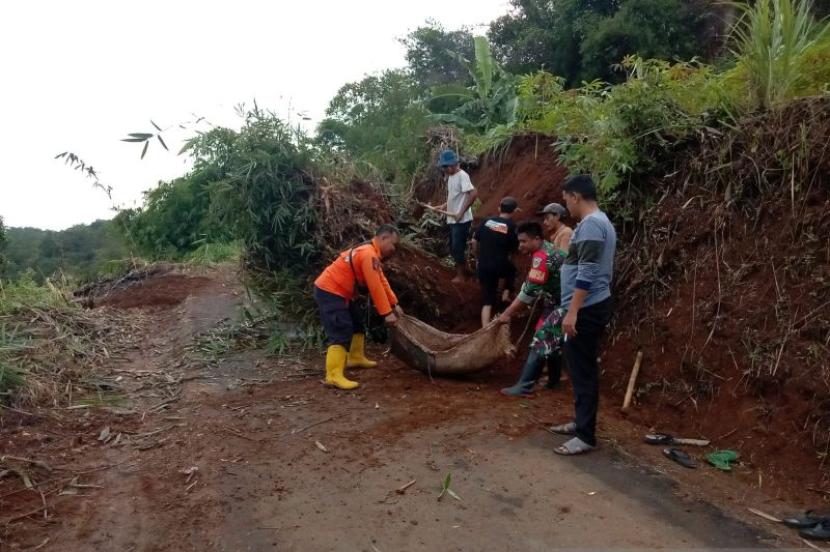Petugas gabungan tengah mengevakuasi material tanah yang longsor dan menutup akses jalan desa di Kampung Kutabatu, RT 04/06, Desa Cibolang, Kecamatan Gunungguruh, Kabupaten Sukabumi, Jabar pada Sabtu (20/1/2024). 