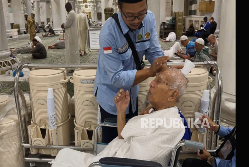 Petugas haji Abdurrahman membasuh air zamzam ke wajah jamaah lansia Soemarmo (93 tahun) sebelum pendorongan kursi roda ke area tawaf Masjidil Haram untuk umroh wajib, Kamis (29/5/2025).