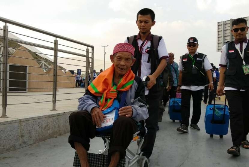 Petugas Haji Daker Bandara menuntun jamaah Kloter 63 Debarkasi Jakarta-Bekasi menuju paviliun Bandara Amir Muhammad bin Abdulaziz, Madinah, Selasa (25/9). Kloter tersebut merupakan kloter terakhir yang dipulangkan ke Tanah Air pada musim haji tahun ini.