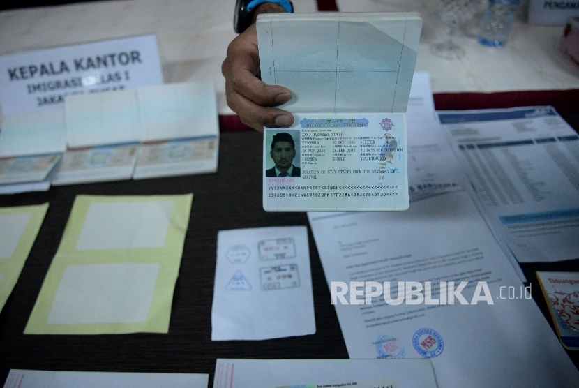 Petugas imigrasi menunjukan barang bukti dan tersangka saat rilis sindikat internasional pemalsuan dokumen keimigrasian di Kantor Imigrasi Jakarta Pusat, Rabu (18/1). 
