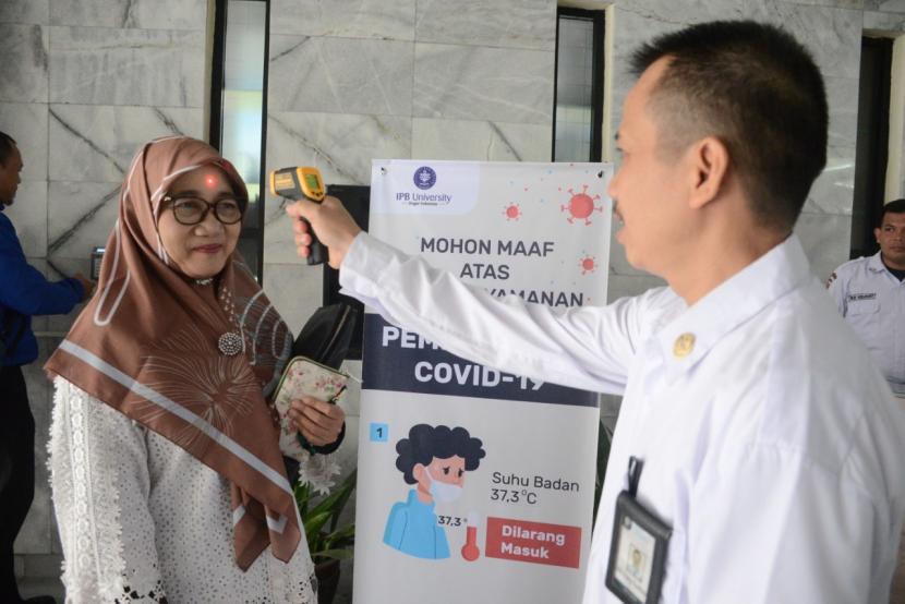 Petugas IPB University memeriksa suhu tubuh warga IPB yang datang ke  gedung rektorat IPB. Salah seorang mahasiswa IPB tertular Covid-19 dari ayahnya yang berdomisili di Jakarta.