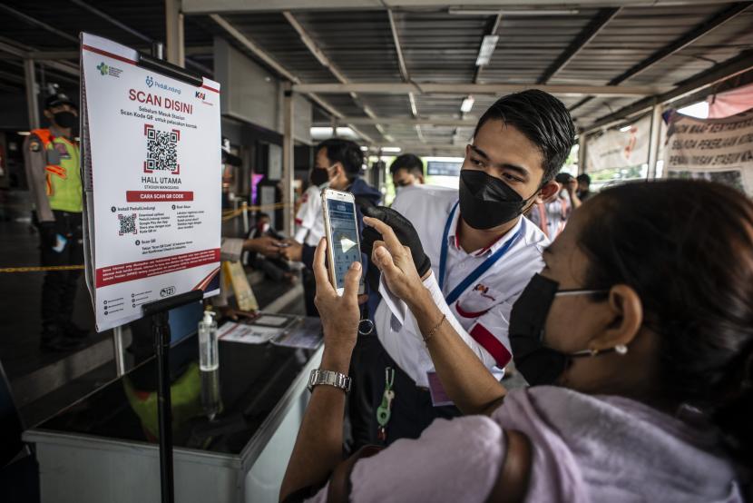 Petugas KAI Commuter membantu calon penumpang memindai kode batang (QR Code) melalui aplikasi PeduliLindungi sebelum menaiki KRL di Stasiun Manggarai, Jakarta, Selasa (7/9). KAI Commuter mencat penurunan jumlah penumpang kereta rel listrik (KRL) usai libur Natal 2021.