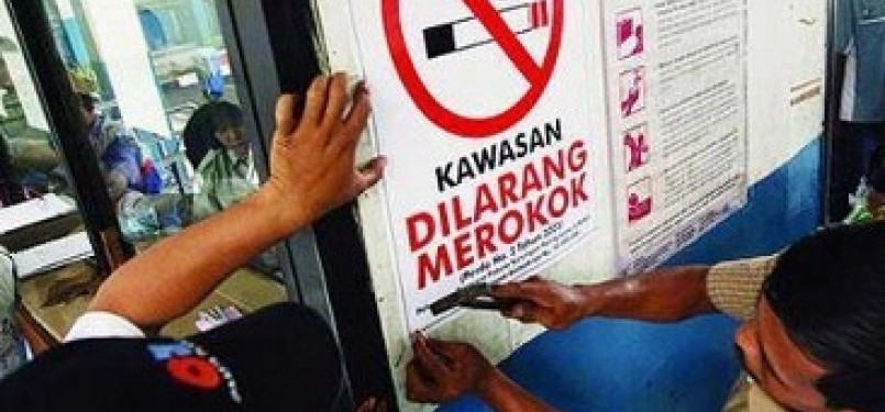 Petugas KAI memasang pengumuman dilarang merokok di seluruh gerbong di kereta api di sebuah stasiun
