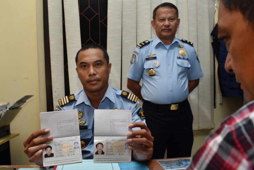 Petugas Kantor Imigrasi Madiun menunjukkan dua paspor warga Tiongkok sebelum dideportasi dari Kantor Imigrasi Madiun, Jawa Timur, Jumat (30/12). 