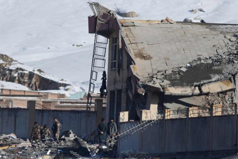 Petugas keamanan Afghanistan memeriksa gedung yang roboh pacsaserangan yang dilakuksan Taliban dan menyebabkan lebih dari 100 orang tewas.  