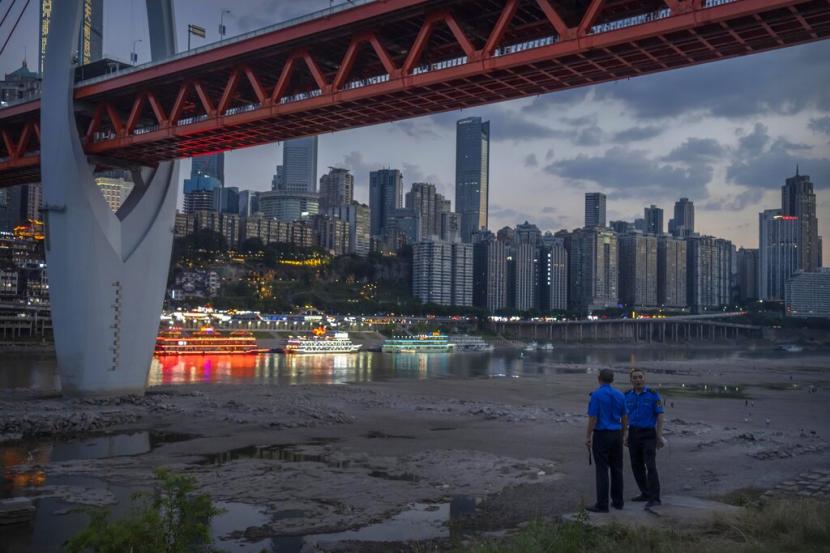 Petugas keamanan berdiri di lereng bukit setelah membersihkan pengunjung dari dasar sungai kering Sungai Jialing, anak sungai Yangtze, di Kotamadya Chongqing, China barat daya, 20 Agustus 2022. Pihak berwenang di pusat keuangan China kota Shanghai telah memberi tahu warga bahwa pasokan air kota tetap normal.