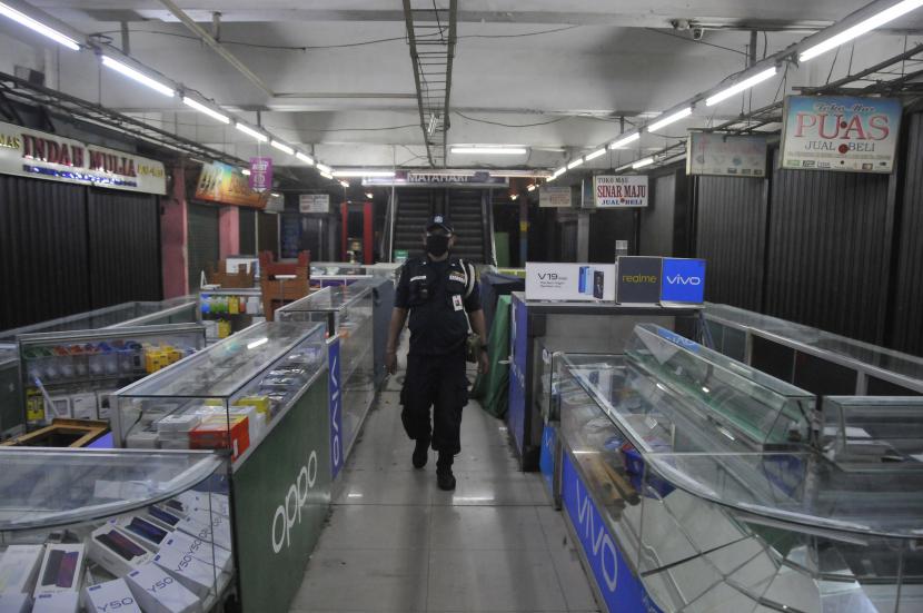 Petugas keamanan berjaga di pertokoan pasar Perumnas yang tutup, Jakarta Timur, Kamis (4/6/2020). Penutupan pasar Perumnas tersebut terkait adanya 20 pedagang yang positif COVID-19 dari penambahan kasus sebanyak 15 orang usai tes swab gelombang dua yang dilakukan Puskesmas Duren Sawit