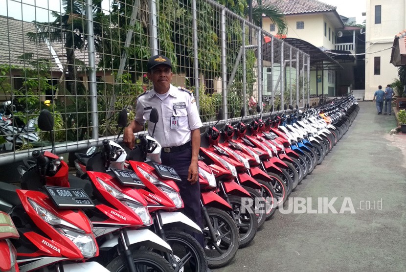 Petugas keamanan di SMAN 4 Kota Tangerang Selatan (Tangsel) menyusun motor yang terpakir sesuai warna motor.