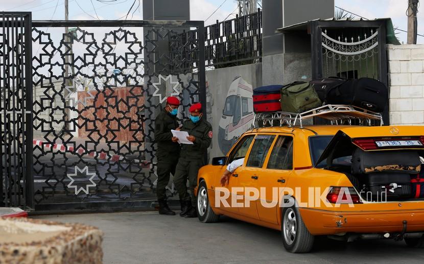 Petugas keamanan Hamas melakukan pengecekan daftar penumpang sembari menunggu di pintu gerbang lintas perbatasan ke perlintasan Rafah sisi Mesir, di Rafah, Jalur Gaza, Selasa (11/8/2020).