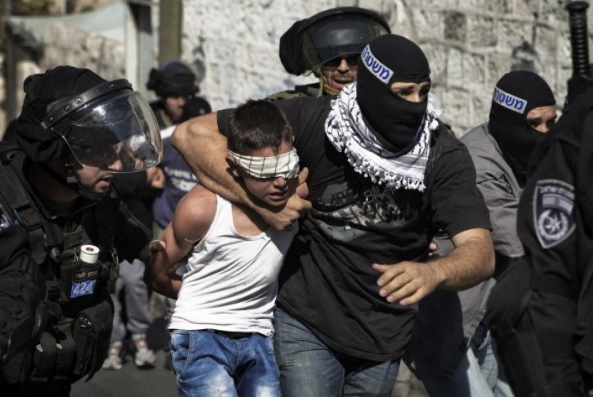 Petugas keamanan menangkap remaja Palestina.