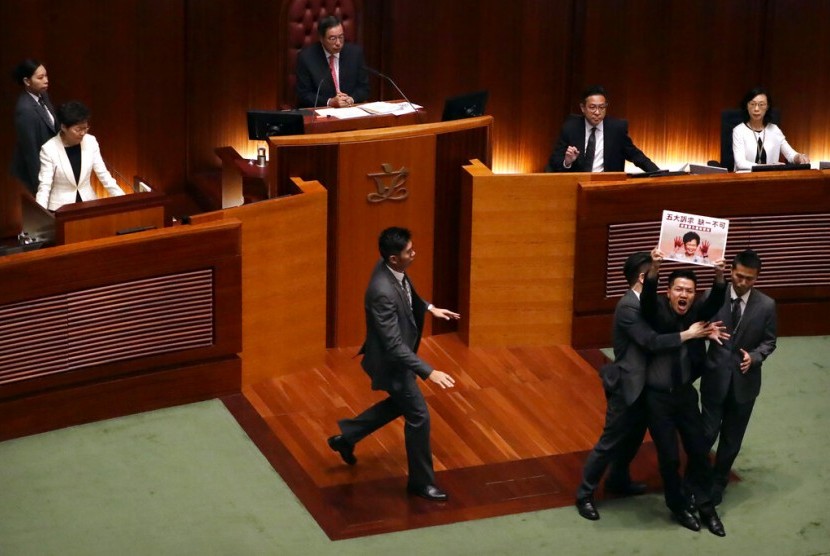 Petugas keamanan mengamankan anggota parlemen pro demokrasi Au Nok-hin yang berlari ke arah Ketua Eksekutif Hong Kong Carrie Lam saat berpidato di Majelis Legislatif, Hong Kong, Kamis (17/10).