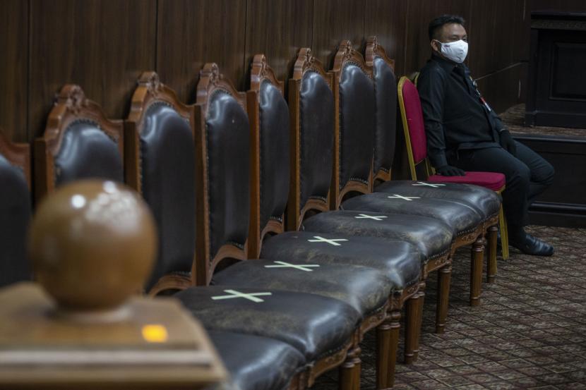 Petugas keamanan menggunakan masker dan sarung tangan saat mengikuti sidang Pengujian Materiil di Mahkamah Konstitusi (MK).