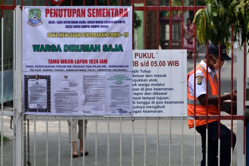 Petugas keamanan menjaga pintu masuk salah satu perumahan yang telah dipasang imbauan agar warga berada di rumah saja di Bekasi, Jawa Barat, Ahad (29/3/2020). Pemerintah Kota (Pemkot) Bekasi berencana melakukan isolasi kemanusiaan guna mencegah penyebaran Virus Corona (Covid-19) yang akan diterapkan pada Senin (30/3/2020) dan proteksi dimulai dari lingkungan Rukun Tetangga (RT) dan Rukun Warga (RW).