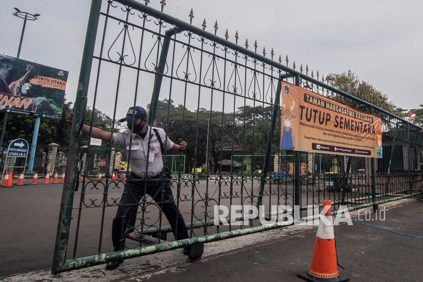 Petugas keamanan menutup pintu masuk Taman Margasatwa Ragunan yang ditutup operasionalnya di Jakarta, Rabu (23/6/2021). Kawasan wisata tersebut ditutup dikarenakan adanya peningkatan kasus COVID-19 di Jakarta, hingga batas waktu yang belum ditentukan. 