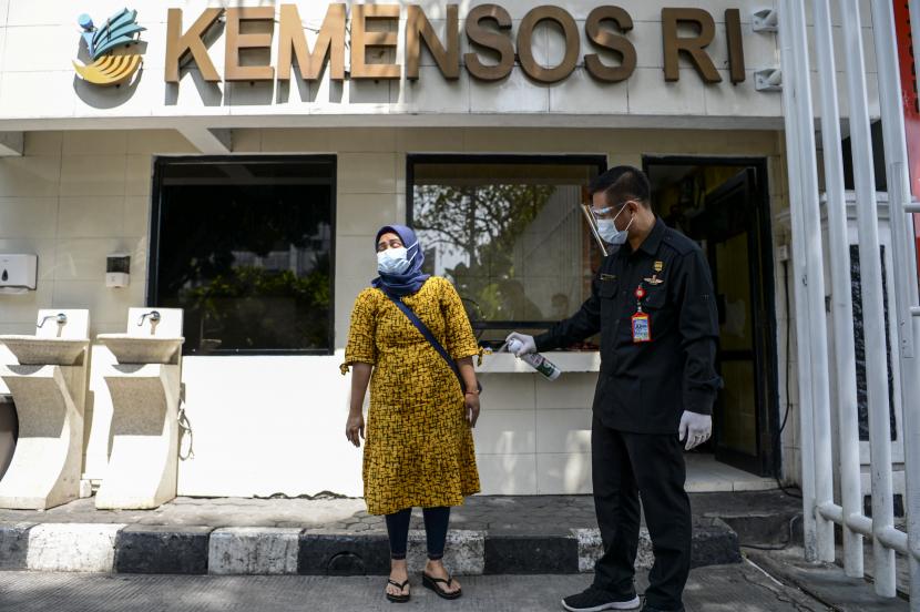 Petugas keamanan menyemprotkan cairan disinfektan pada pedagang yang berdagang di depan Kantor Pusat Kementerian Sosial (Kemensos), Jakarta, Jumat (28/1/2022). Kantor Kemensos melakukan penguncian wilayah sementara hingga Senin (31/1/2022) mendatang tersebut dikarenakan adanya temuan 60 pegawai positif terpapar COVID-19.
