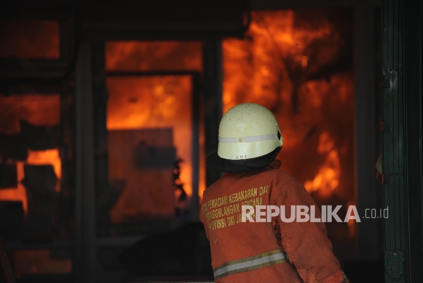 Petugas kebakaran berada di sejumlah pertokoan yang terbakar di jalan Sabang, Jakarta, Ahad (08/10). 