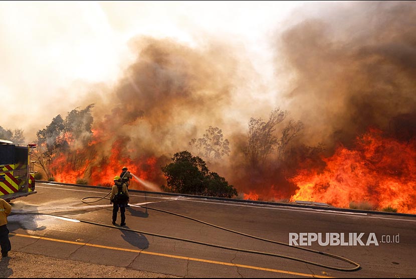 Petugas kebakaran berusaha memadamkan api di jalan Ronald Reagan, Simmi Valley, Kalifornia (12/11) waktu setempat.