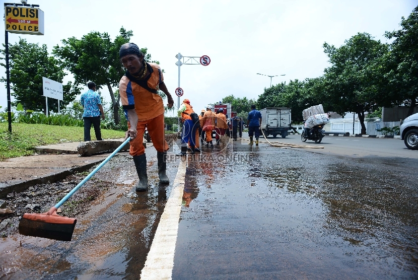 Petugas kebersihan bersama petugas pemadam kebakaran membersihkan lumpur yang mengerak akibat banjir di Kawasan Pluit, Jakarta Utara, Kamis (12/2). 