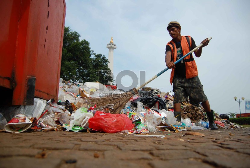  Petugas kebersihan membersihkan sampah yang berada di pelataran Monumen Nasional, Jakarta Pusat, Kamis (31/7). (Republika/Raisan Al Farisi)