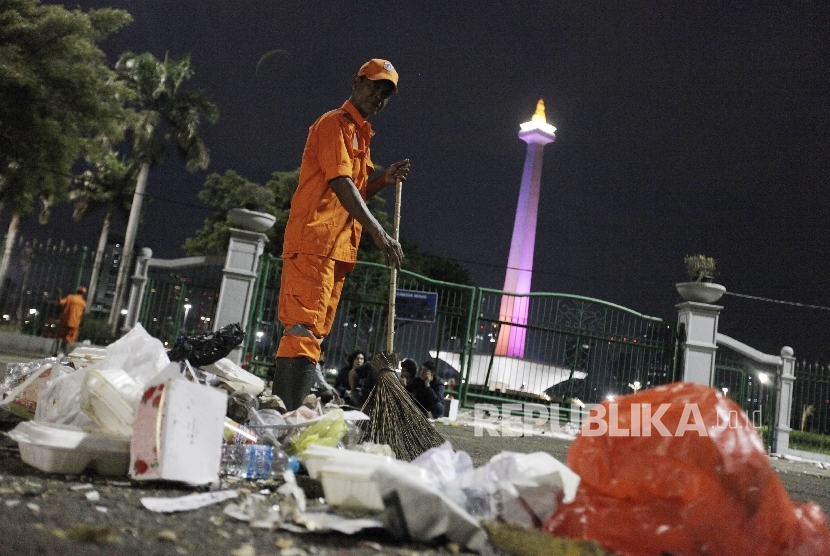  Petugas kebersihan membersihkan sisa sampah warga yang merayakan tahun baru di kawasan Monas, Jakarta Pusat, Ahad (1/1). 