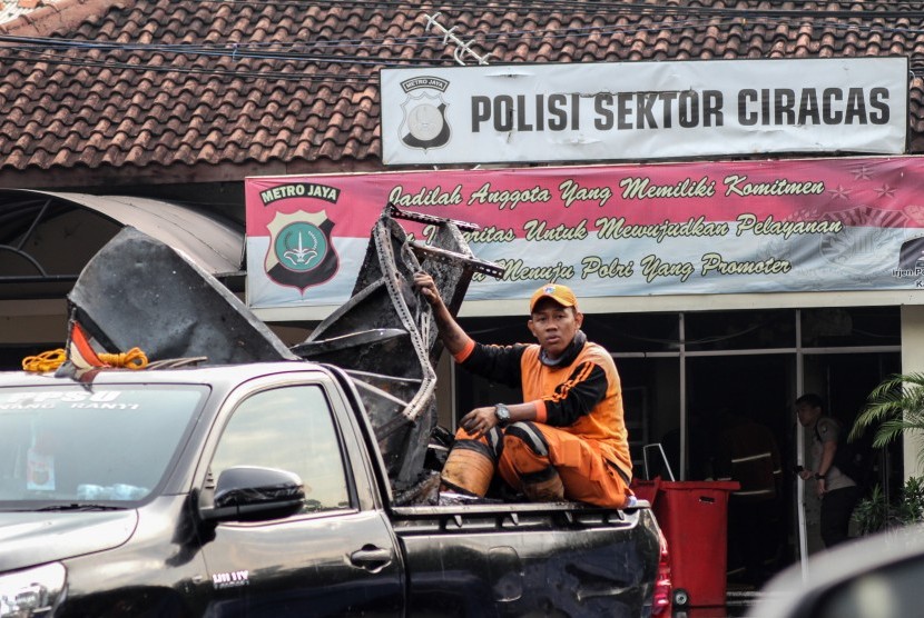 Petugas kebersihan mengangkut barang sisa perusakan dan pembakaran di Polsek Ciracas, Jakarta, Rabu (12/12/2018). 