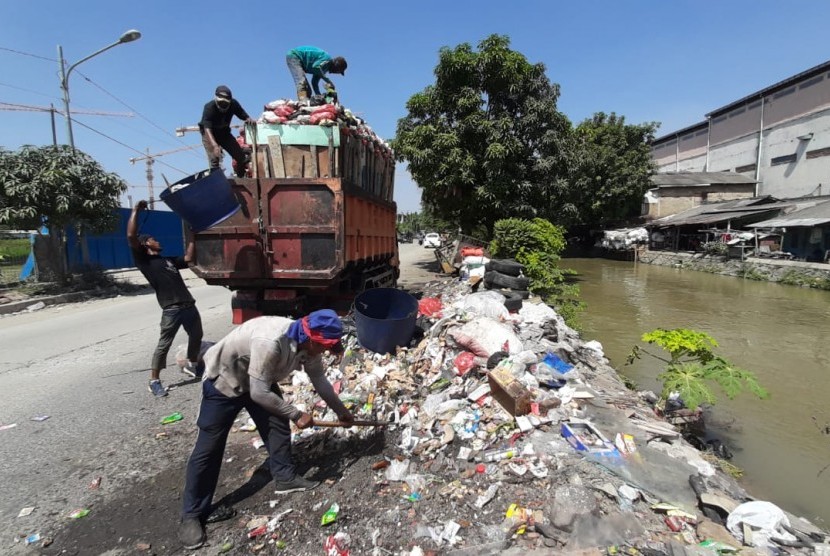 Petugas kebersihan pada Dinas Lingkungan Hidup Kota Bekasi sedang membersihkan sampah yang menumpuk di Tempat Pembuangan Sementara (TPS) di Jalan Irigasi Gempol, Kelurahan Medan Satria, Kecamatan Medan Satria, Rabu (19/6).