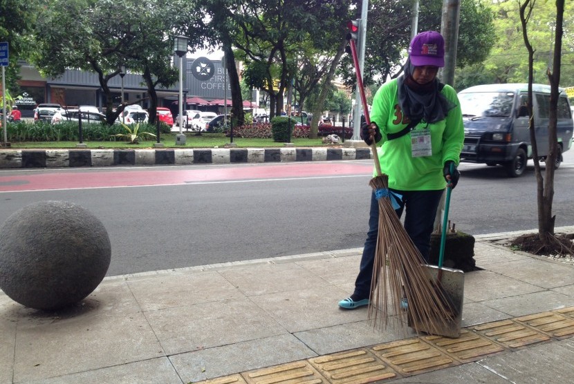 Petugas kebersihan sedang membersihkan trotoar di salah satu sudut Kota Bandung.
