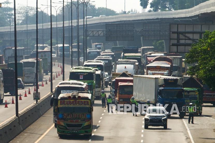 Petugas kepolisan mengatur lalu lintas kendaraan saat pemberlakuan rekayasa lalu lintas di jalan tol Jakarta - Cikampek (Japek) KM 40. PT Jasa Marga bersama pihak kepolisian memberlakukan sistem 