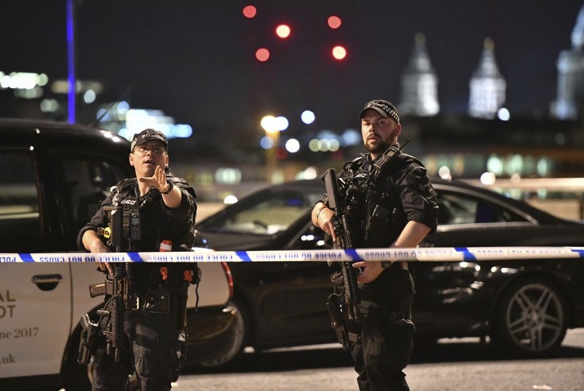 Petugas kepolisian berjaga di Jembatan London setelah insiden van yang menabrakkan kendaraannya ke jalur pedesterian, Ahad (4/6).