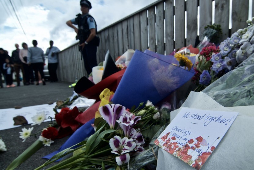 Petugas kepolisian berjaga didekat bunga yang diletakkan warga di depan Masjid Wellington, Kilbirnie, Wellington, Selandia Baru, Sabtu (16/3/2019).