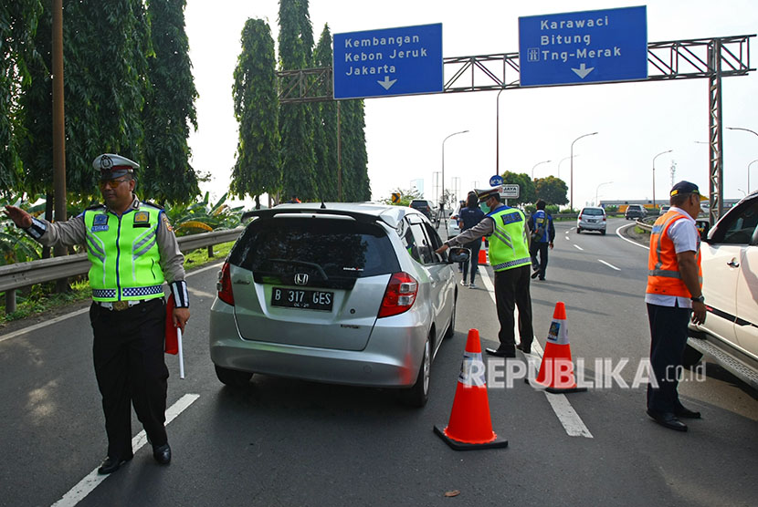 Petugas kepolisian bersama petugas Jasa Marga menghalau pengendara berpelat nomor ganjil yang akan memasuki tol Jakarta - Tangerang (Janger) saat dimulainya hari pertama uji coba penerapan sistem ganjil genap di Gerbang Tol Tangerang 2, Tangerang, Banten, Senin (16/4). 