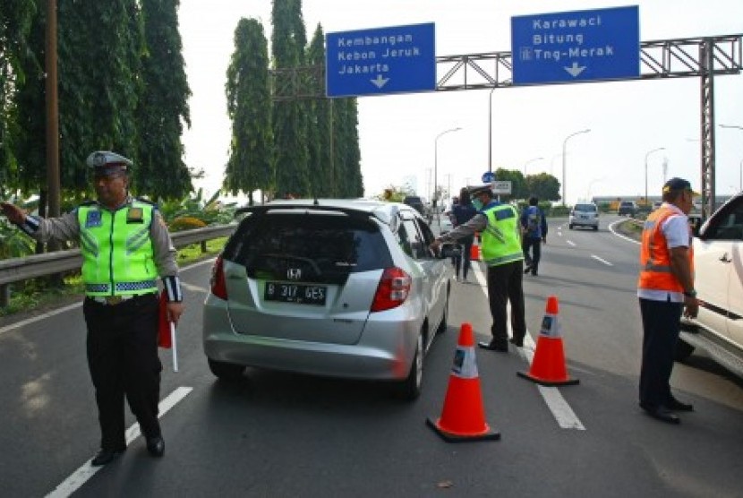 Petugas kepolisian bersama petugas Jasa Marga menghalau pengendara berpelat nomor ganjil yang akan memasuki tol Jakarta-Tangerang (Janger) saat hari pertama uji coba penerapan sistem ganjil genap di Gerbang Tol Tangerang 2, Tangerang, Banten, Senin (16/4). 