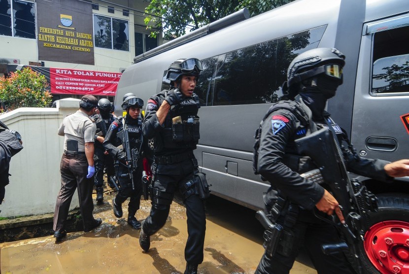 Petugas kepolisian bersenjata lengkap bergegas keluar seusai berhasil menangkap terduga teroris di Kantor Kelurahan Arjuna, Bandung, Jawa Barat, Senin (27/2).