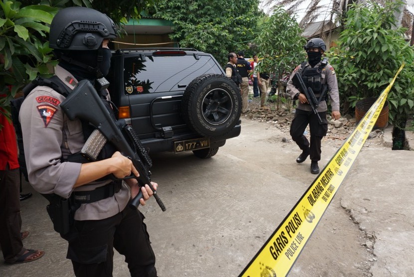 Petugas kepolisian bersenjata lengkap berjaga di rumah pelaku teror polisi saat dilakukan penggeledahan, di Sepatan, Kabupaten Tangerang, Banten, Kamis (20/10). 